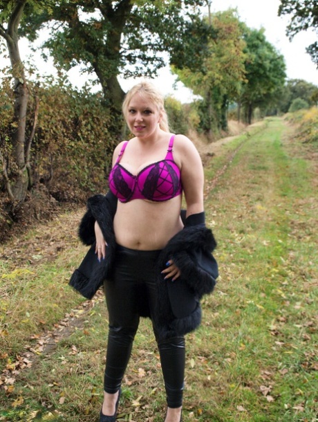 Blond amateur girl named Sindy Bust loosens her large breasts near a farmer's field.
