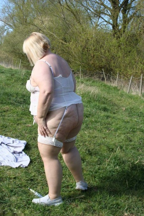 UK amateur Lexie Cummings flaunts her large buttocks and piercings in a field.