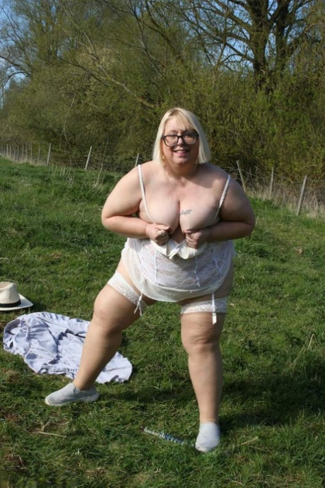 Lexie Cummings, a UK amateur athlete with a large penis, displays her vagina and pierced pegasus in a field.