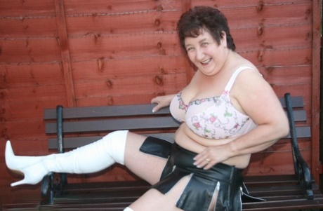 A bra and a microskirt are worn by Kinky Carol, an overweight elderly woman, with over-the-knel boots.