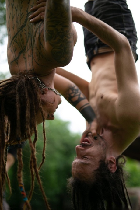 A tattooed couple, Andreaz & Burbz Z, are hanging upside down in a yard display.