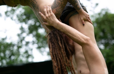 In a yard, Andreaz & Burbz Z, a tattooed couple, are hanging upside down.