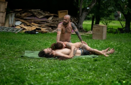 In a yard, Andreaz & Burbz Z, a tattooed couple, are hanging upside down.