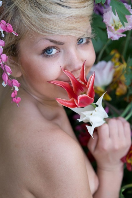 A charming young blonde named Iveta poses in the nude in a garden.