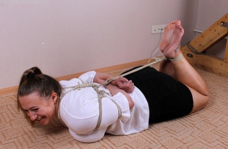 Charlotte, a white woman, is dressed in a blouse and miniskirt, while also being hogtied.