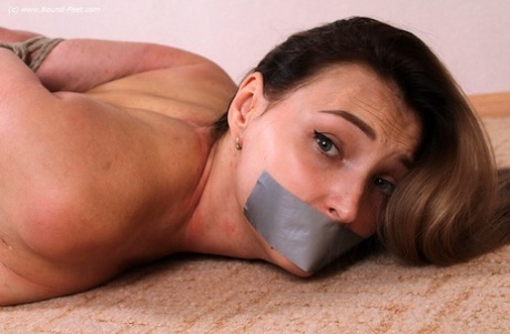 Woman with tattooed hands struggles while bedecked with duct tape and tied up in the nude.