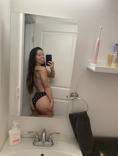 Abbie Maley, a brunette enthusiast who takes mirror selfies with her bare buttocks, demonstrates this behavior by grabbing her ass.
