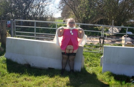 Outside, Lexie Cummings demonstrates her large buttock and anus while being photographed with other women. She is an obese British blonde from the UK.