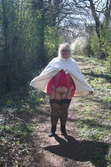 In a field, Lexie Cummings, an obese British blonde, exposes her stomach and large buttocks.