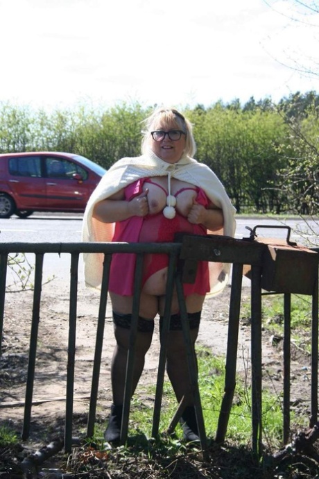 In a field, Lexie Cummings, an Obsessed UK blonde, exposes her stomach and large buttocks.