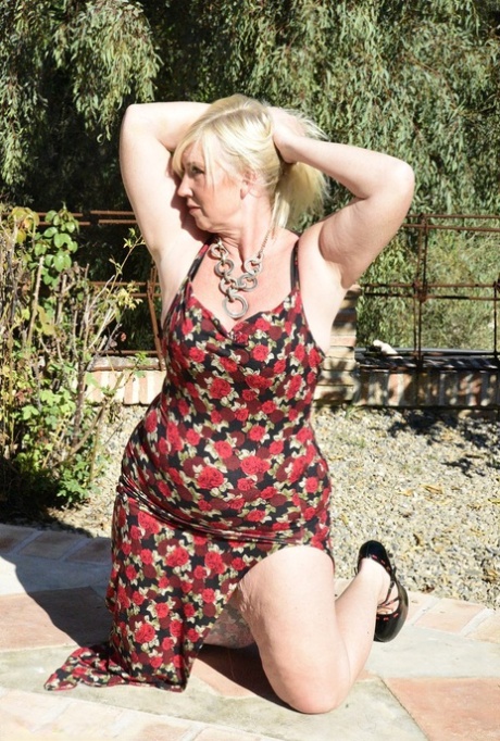 Blonde blonde Melanie loses her large buttock on a long dress while outdoors.