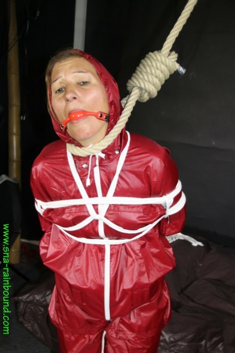 Using her restraints, Sandra wears a ball gag and tie herself up with a raincoat.