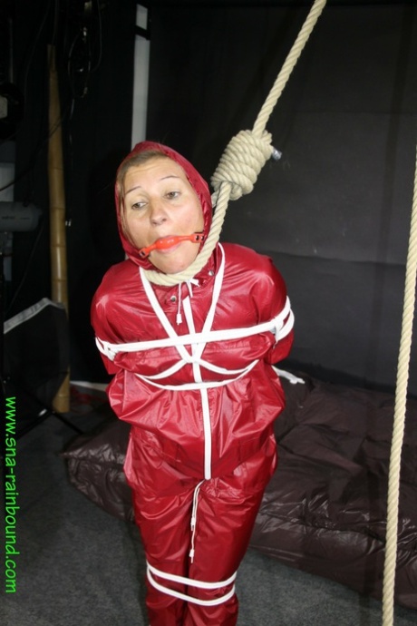 In a raincoat, Sandra is seen wearing a ball gag and tied up as a girl.