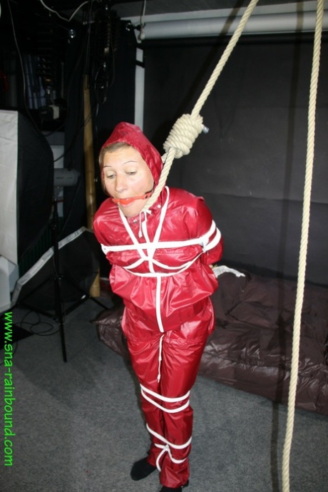 She's got to be Sandra who is wearing the restraints on, tied around her with a ball gag and tied up in a raincoat.