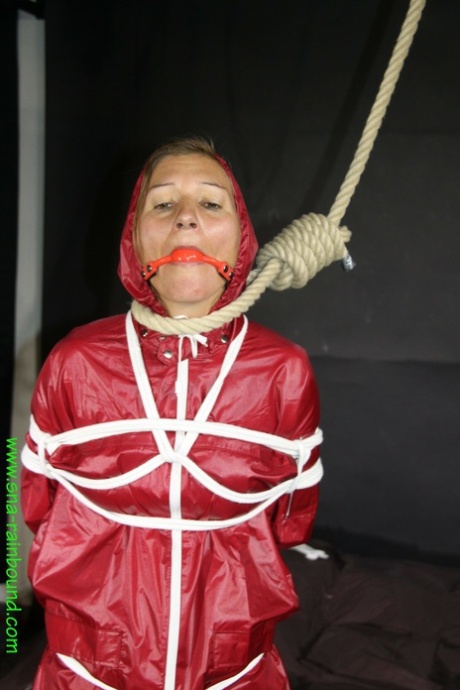 With a ball gag and a noose on her back, Sandra is dressed in a raincoat.