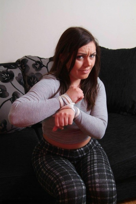 British chick Kacie James is bound with rope on a loveseat while fully clothed