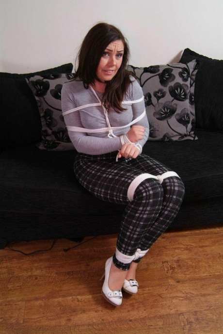 British chick Kacie James is bound with rope on a loveseat while fully clothed