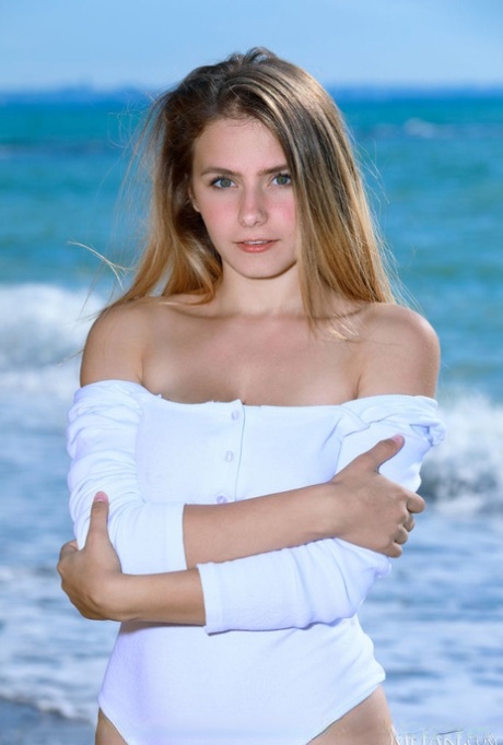 Подростковая модель Дакота Пинк показывает свое красивое тело на галечном пляже