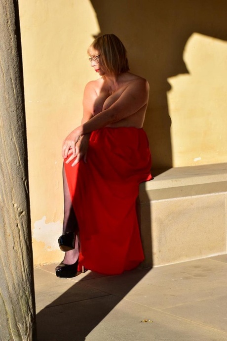 Wearing a red evening gown, Barby Slut, who is older than her age, poses nude in hosiery.