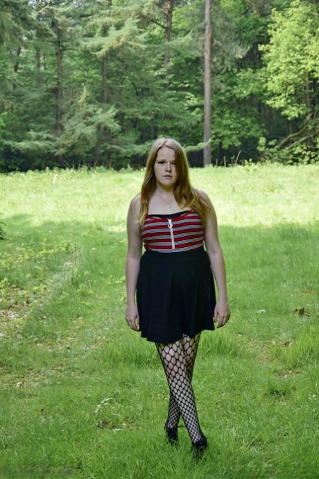 In a field, a redheaded amateur displays her tits during upskirt action.