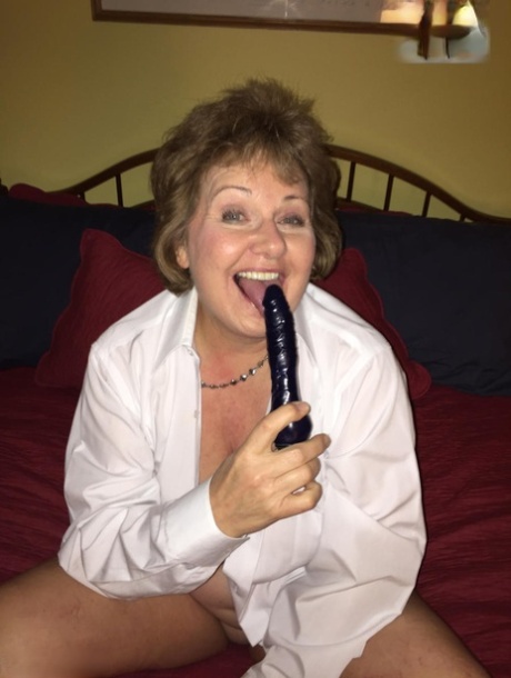 Busty Bliss, a mature woman, uses a sex toy to stimulate her penis while playing.