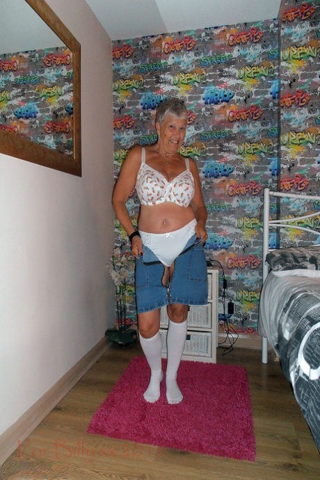 The granny with silver hair in her bedroom bares white knee socks.