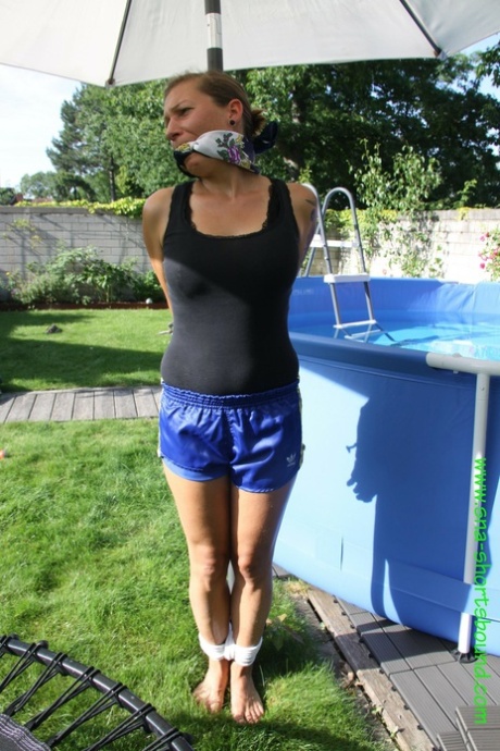 A naked female, Sandra, has her clothes on a clothesline tied to an umbrella stand.