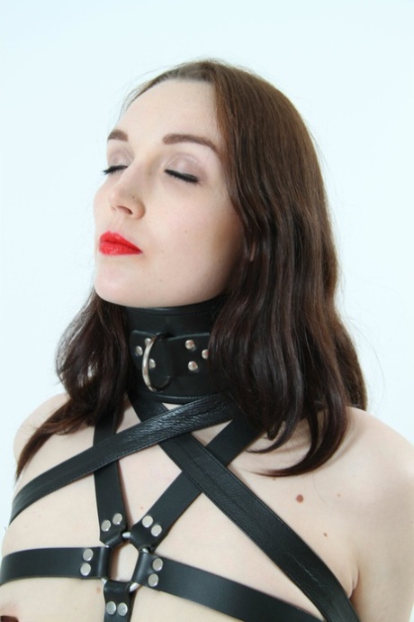 Beautiful Girl Models Leather BDSM Attire With Her Arms Restrained Behind Her