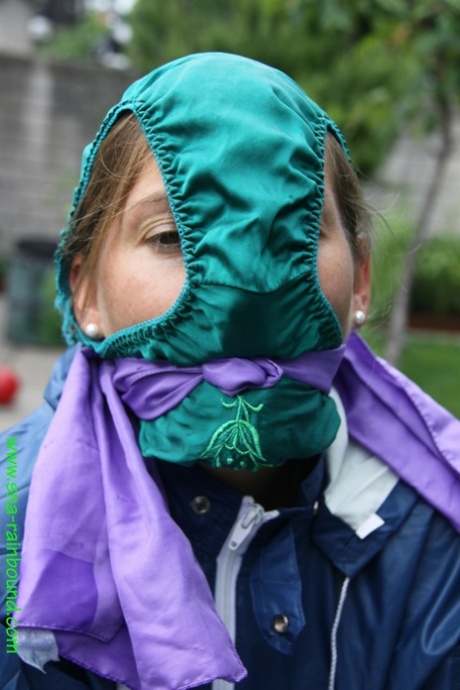 Caucasian woman tied to a table in the yard, wearing panties covering her face.