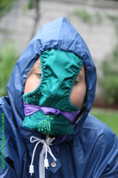 In a yard, a white woman is restrained to the table with panties draped over her face.