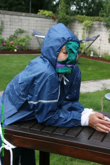 One: A white woman tied down in a yard, with her panties draped over her face, is seen here holding onto a table.