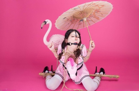 Following her being tied up and ball gagged, Coco, an Asian solo girl, holds a parasol and continues to hold it in knots.