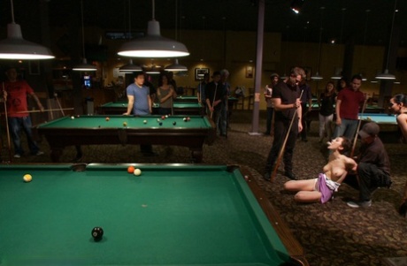 The exposed skin of a naked brunette is trapped and penetrated inside a billiards room.