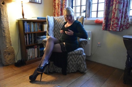 The vagina is exposed while Barby Slut, an older blonde lady, performs upskirt action on a chair.