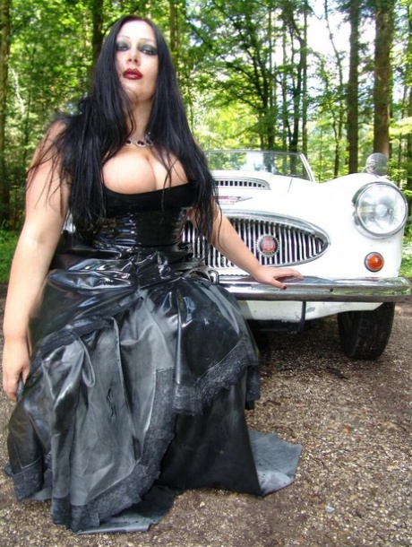 During her hikes in the wooded area, Lady Angelina, a goth woman, sheds her sizable breasts on top of a car.