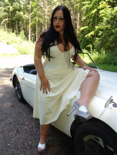 The goth Lady Angelina is seen in a vehicle loosening her large breasts from a dress.