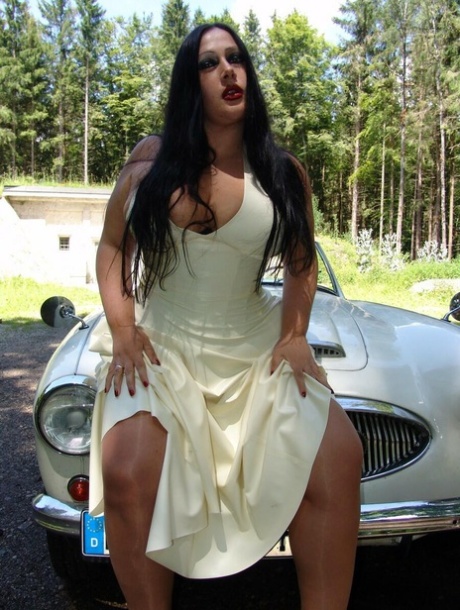 Lady Angelina, a gothic performer, removes her sizable breasts from a dress in a vehicle.