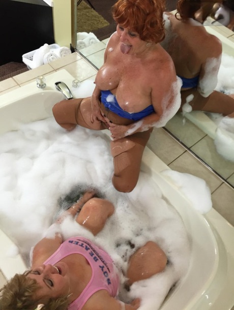 A bubble bath is a place where Busty Bliss, an older adult performs lesbian intercourse.