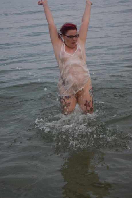 Moist Mollie Foxxx, a redhead at the age of five years old, wets her tattooed body in the ocean.