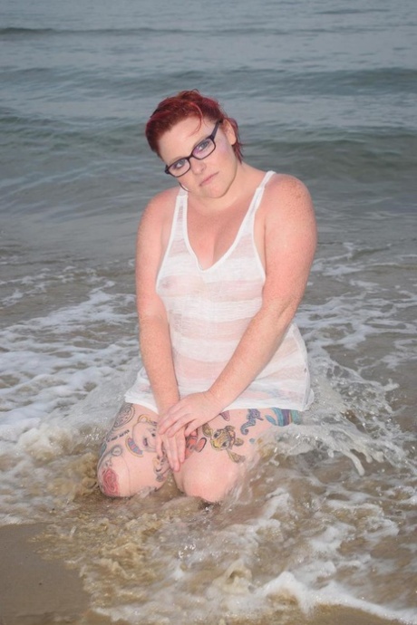 Mollie Foxxx, a young and active redhead, infuses her tattooed body with water while swimming in the ocean.