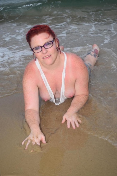 Mature redhead Mollie Foxxx wets her tattooed body in the ocean