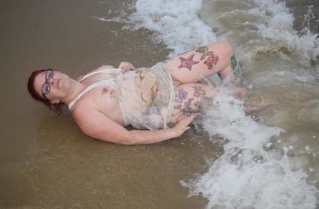 At six years old, Mollie Foxxx, a young redhead, sweats on her tattooed body in the sea as a result of being exposed to the elements.