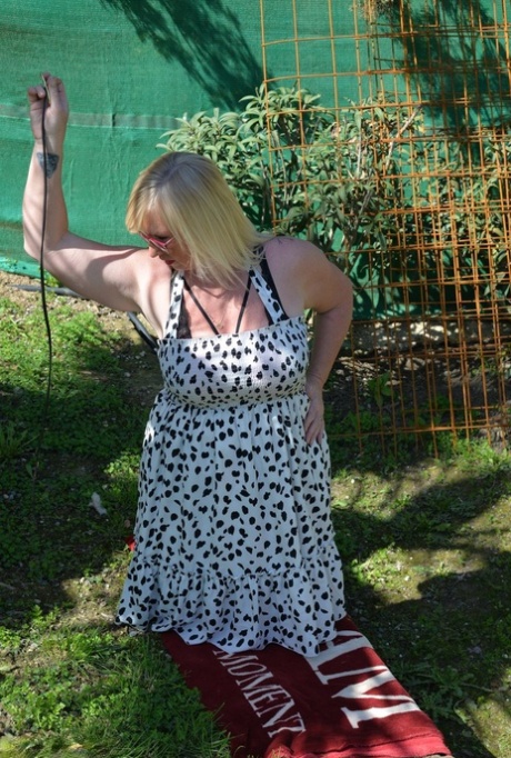 Melody, a mature blonde with fat, exposes her ample bosom in a backyard.