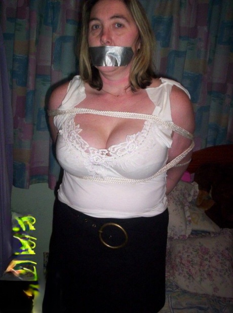 Gagged and roped, the white woman displays her natural tits.