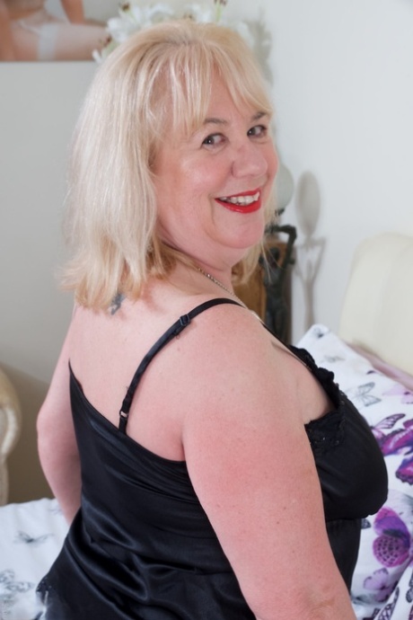 Зрелая толстушка из Великобритании Спиди Би снимает черное неглиже на кровати в нейлоновом белье со швом сзади