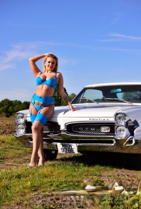 British solo girl Lycia Sharyl displays her great tits in front of an elderly Pontiac.