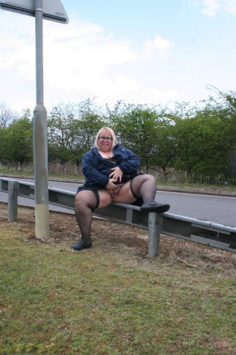 Obese UK blonde Lexie Cummings pees on a concrete block by the roadside.