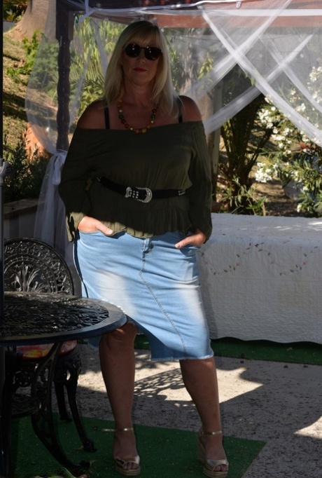 Melody, the overweight blonde, fondles her breasts while wearing sunglasses outside.