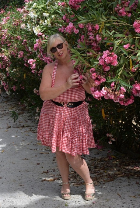 Melody, who is a fat and mature blonde, enjoys playing with her massive breasts in a rose garden.