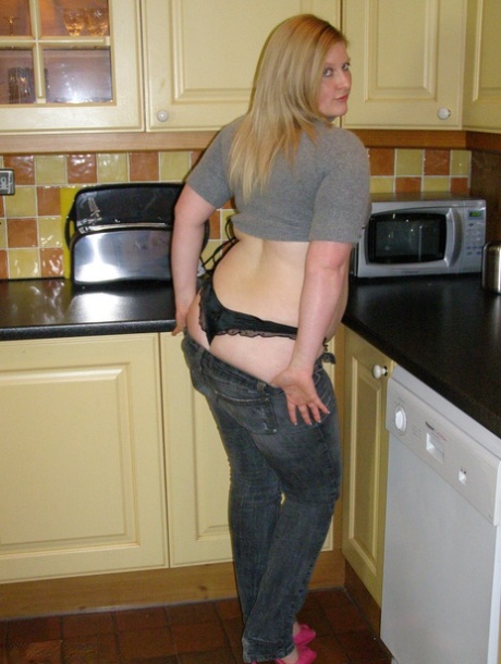 In the kitchen, Samantha, a novice plumper, exposes her large buttocks and seizes them.